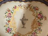 a decorative plate with a vase on it on a table
