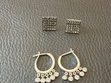 une paire de boucles d'oreilles et une autre paire de boucles d'oreilles posées sur une surface en cuir