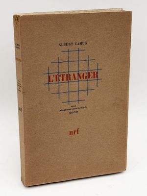 un livre marron avec des lettres rouges, posé sur une surface blanche