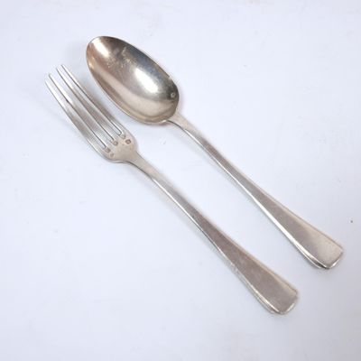 two spoons and a fork on a white table
