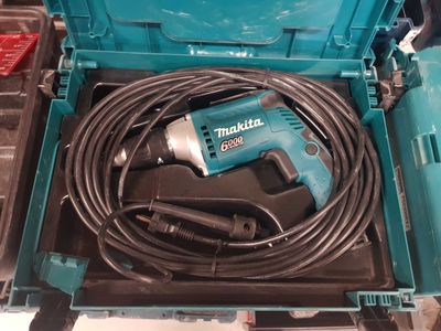 une perceuse filaire dans une boîte à outils, avec son cordon d'alimentation