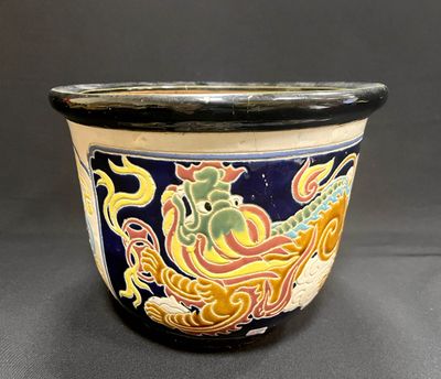 un pot noir et jaune orné d'un motif représentant un dragon