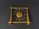 a gold clock on a black table with a black background