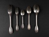 five silver spoons and a fork on a black surface