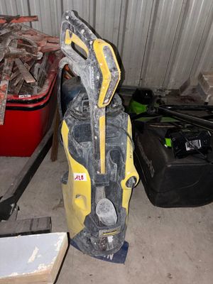 un aspirateur jaune et noir posé sur un sol sale, à côté d'un tas de vieilleries