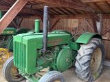 un tracteur vert garé à l'intérieur d'une grange au toit en bois