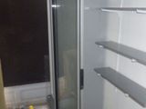 a glass door in the corner of a room with shelves