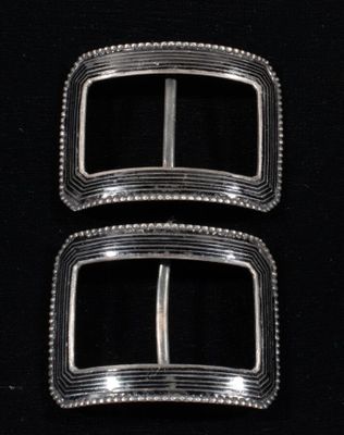 two silver buckles on a black background with a black background