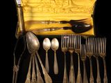 a lot of silver spoons and silverware in a box