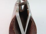 a brown leather purse with a metal handle on a white surface