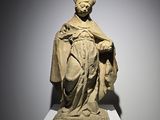 une statue représentant un homme coiffé d'un chapeau et vêtu d'une robe, posée sur un socle