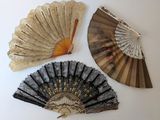 trois vieux ventilateurs sont exposés sur une surface blanche
