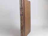 a brown book sitting on top of a table next to a white wall