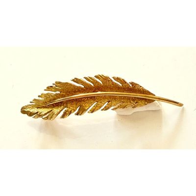 une image représentant une broche en forme de plume de couleur dorée