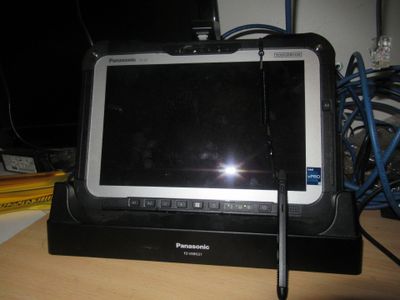 a tablet computer sitting on a desk with a pen in front of it