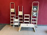 plusieurs échelles et une table dans une pièce dont l'un des murs est rouge