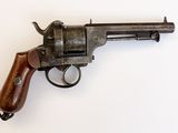 un vieux revolver avec une poignée en bois sur une surface blanche
