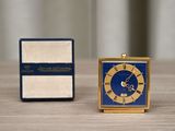 a small clock sitting next to a small box on a table