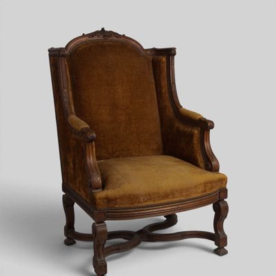an old fashioned chair with a brown upholstered seat
