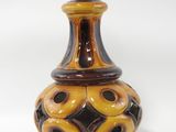 un vase brun et noir posé sur une surface blanche