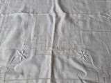 a white table cloth with a design on it on a bed