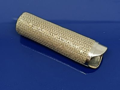 une image représentant un briquet doré posé sur une surface bleue