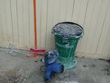 a green trash can and a blue fire hydrant on the side of a building