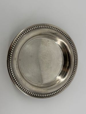 a close up of a silver plate with a beaded edge