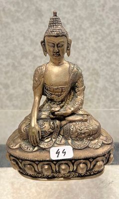 statue en laiton représentant un Bouddha assis, posée sur une table, avec une étiquette de prix devant