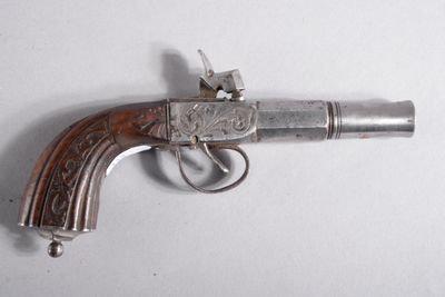 un pistolet ancien plaqué argent, avec une crosse en bois, posé sur une surface blanche