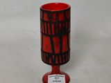 un vase rouge orné d'un motif en noir et blanc