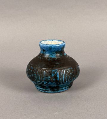 a small blue vase sitting on a gray surface