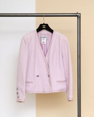 une veste rose suspendue à un cintre devant un mur beige