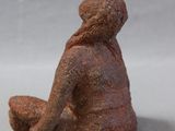 two figurines of a woman sitting on the ground next to each other