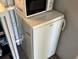 a microwave on top of a small refrigerator in a small room