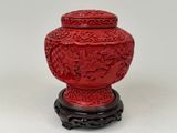 a red vase that is sitting on a stand