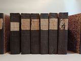 several old books are lined up in a row on a table