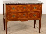 une commode au plateau en marbre posée sur une table en bois
