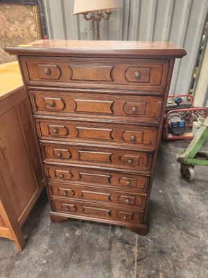 une commode en bois avec des tiroirs, sur laquelle est posée une lampe