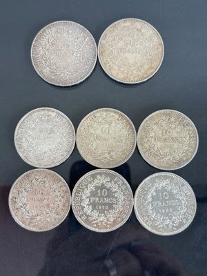 Six pièces de monnaie britanniques différentes sont exposées dans une vitrine.