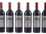 six bottles of red wine lined up in a row on a white surface