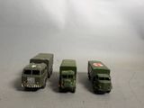 quatre camions militaires miniatures posés les uns à côté des autres sur une table