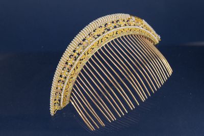 un peigne en or orné de diamants, posé sur un fond bleu