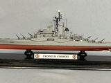 une maquette de bateau posée sur un socle, sur une surface blanche