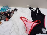 three women ' s swimsuits on a bed with a hanger on the wall