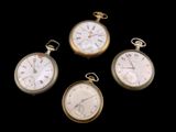 quatre types différents de montres de poche posées sur une surface noire