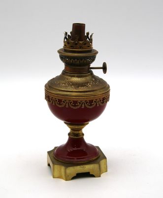 un vase rouge et doré posé sur un socle, sur une surface blanche