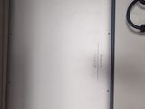 a white tablet computer sitting on a table with a black cord