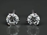 une paire de boucles d'oreilles en diamant posées sur une surface réfléchissante