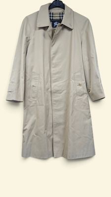 un trench-coat suspendu à un cintre sur un mur blanc